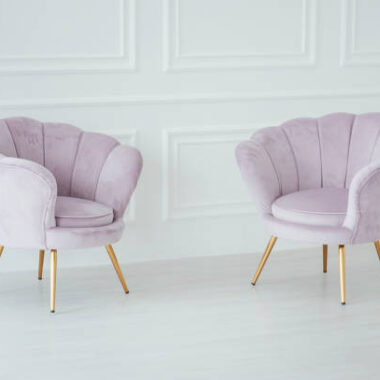 Beautiful and comfortable pink armchairs stand in a spacious room near the wall